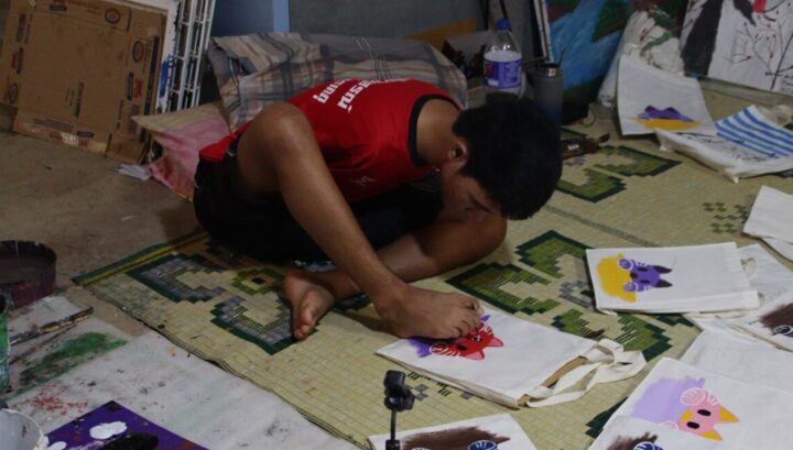 น้องทาม ไร้แขนแต่เกิด แต่ใช้เท้าสู้ชีวิต วาดภาพลงถุงผ้าขาย ช่วยครอบครัว